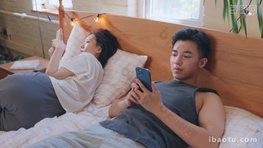 青年情侣躺在床上各自玩手机
